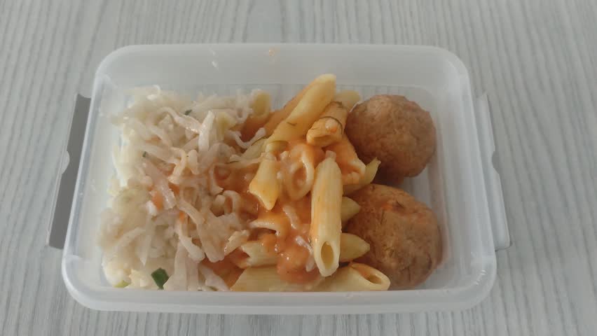 Meatballs with pasta and salad in a food container. Food for lunch in the office