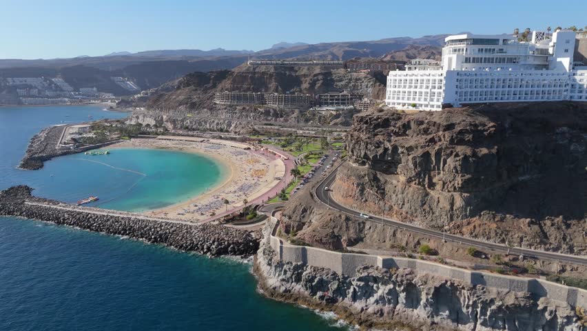 the golden sands of the beach, the majestic cliffs, and the ocean view. The cliffside hotel complements the scenery, offering luxury and comfort, while the beach strip provides a sense of tranquility 