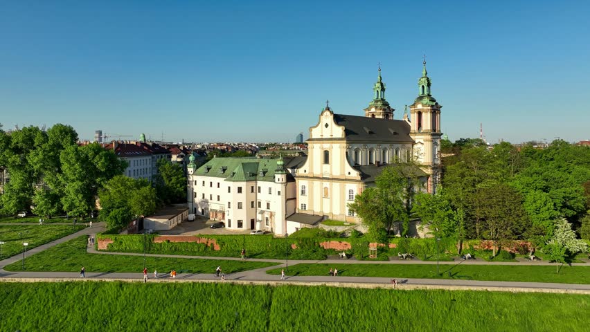 Krakow, Poland. Skalka, St. Stanislaus Baroque church na Skałce and Paulinite monastery. Aerial panning video in spring. People walking on boulevard and promenade. Old town and Wawel in the background