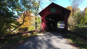 A 4K picturesque fly past, over and through Slaughterhouse Covered Bridge in Northfield Vermont during peak Fall foliage. USA
