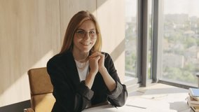 Portrait of a beautiful young redhead woman in the office. The girl In glasses looks at the camera and smiles. Boss girl in office or coworking space - Powered by Shutterstock - Get 15% off with code: PIKWIZARD15