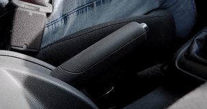 Close-up of a person fastening a seatbelt in a car, safety first concept and bringing down the hand brake