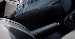 Close-up of a person fastening a seatbelt in a car, safety first concept and bringing up the hand brake
