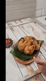 Food  Stylist Applies Oil to Whole Roasted Chicken on Wooden Plate with Banana Leaf, Beautify Food for Appetizing Look