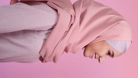 Vertical video. Happy woman. Modest beauty. Positive emotion. Side view portrait of pleased joyful girl in hijab with pretty toothy smile isolated on pastel pink. - Powered by Shutterstock - Get 15% off with code: PIKWIZARD15