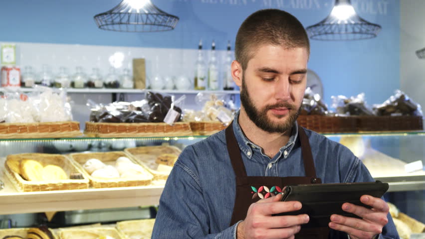 Handsome professional male baker using digital tablet at his store