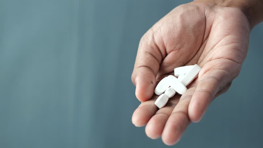 Close up of man hand holding pills on black background 