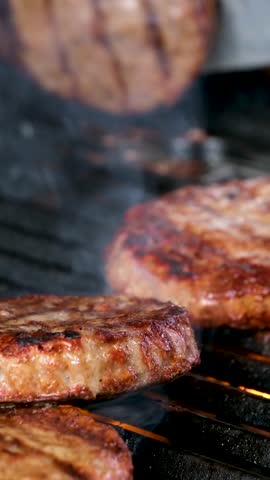 Cooking burgers on a hot grill with a flame Beef cutlets cooked on a barbecue grill.Cooking beef and pork patty for party.