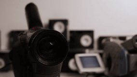 Close up of Old Black Camcorder lens with grey camcorder and tapes in background - Powered by Shutterstock - Get 15% off with code: PIKWIZARD15