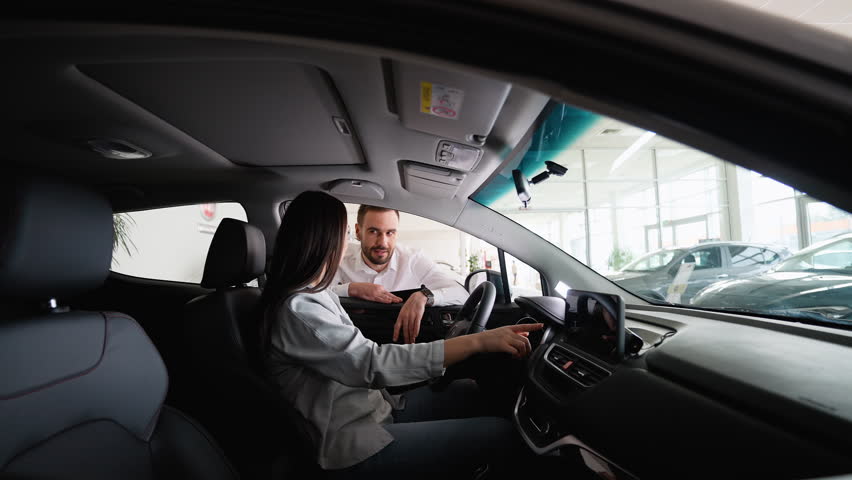 Car seller showing to a female customer car options before buying new car auto