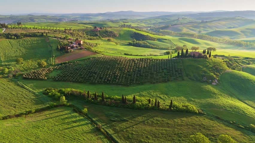 Classic Tuscany landscape with green hills and farmland country at sunrise. Aerial shot of green spring fields and hills in Tuscany, Italy