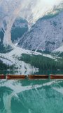 Boats in a lake in Dolomites mountains, Italian Alps, vertical video.