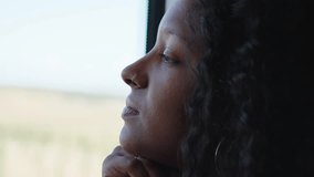 Young African woman traveling on a train, looking through the window enjoying the view and looking pensive. Close up footage with copy space. - Powered by Shutterstock - Get 15% off with code: PIKWIZARD15