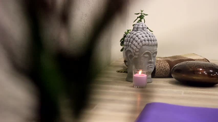 Green leaves of a flower against the background of a Buddha head, Hapi Dram and candles in the video