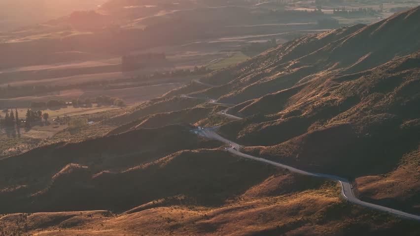 New Zealand scenic winding road over Crown Range to Queenstown, road trip. Autumn sunset. Aerial drone
