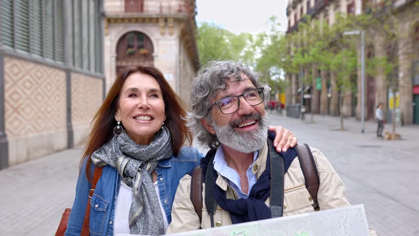 Happy retired senior tourist couple looking for location on city map during travel vacation in Barcelona. Retirement and holiday maker mature people concept.