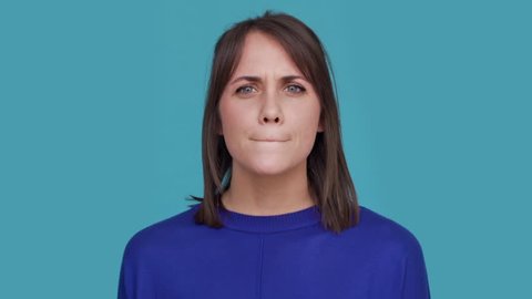 Portrait of concentrated brunette female 30s biting lips thinking about things doubting suddenly finding solution and putting index finger up over blue background. Concept of emotions