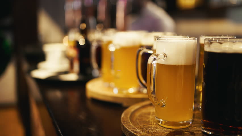 Paulaner hefeweizen beer mugs on wooden tray at bar table