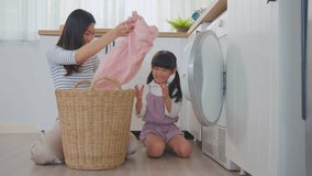 Asian beautiful mother teach young daughter wash dirty clothes at home. Adorable little cute girl child help and learn from parent mom to put laundry in washer appliance at home. Domestic-Housekeeping - Powered by Shutterstock - Get 15% off with code: PIKWIZARD15