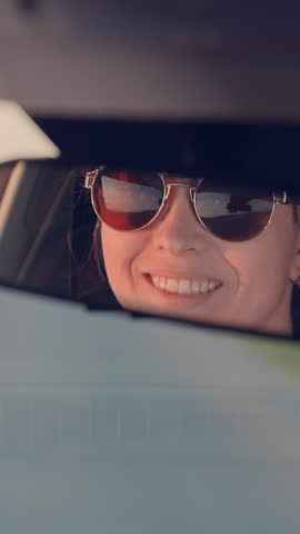 girl in sunglasses, driving in car, looking in mirror, smiling at reflection, driver behind wheel, looking in mirror, front seat passenger, smiling at camera, joyful driving experience, car interior