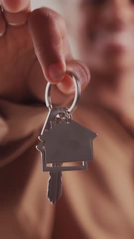 Silver keys to apartment with keychain in shape house in hands of woman boasting about purchase own real estate or opportunity to rent home in good area close to city center. Realtor, agent, broker