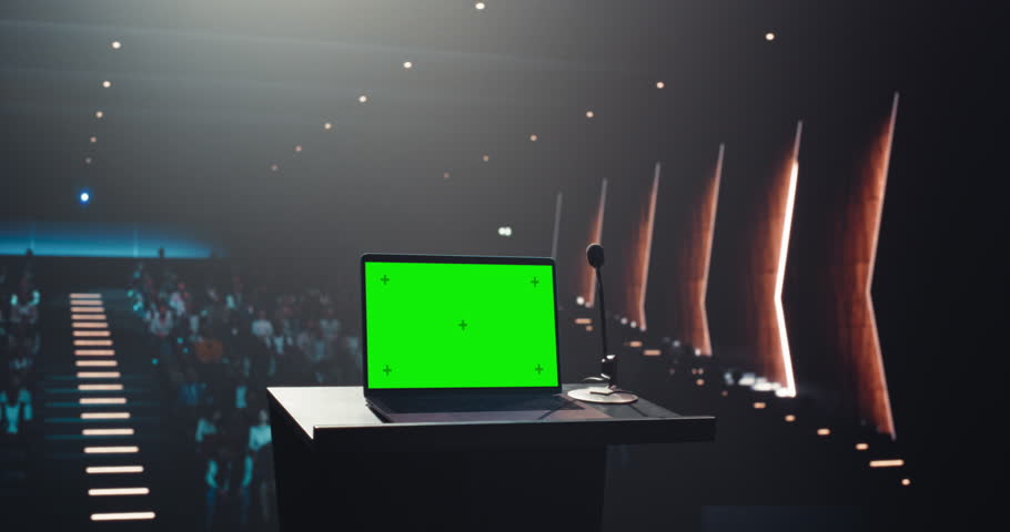 Green Screen Laptop Computer Standing on a Podium at a Conference Hall with Audience in the Background. Template for Business Presentations and Tech Videos, with Room for Custom Content Integration