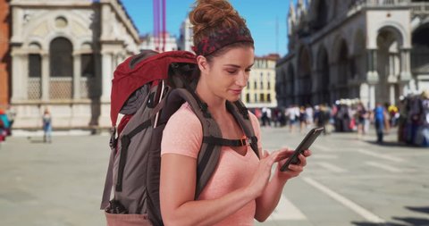 Vacationing white female backpacker checking her smartphone at St. Mark's Square in Venice, Italy. Active young lady reading her recent messages on her mobile Device. 4k