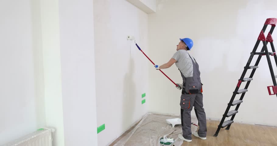 Painter paints wall with roller at construction site. Wall painting Royalty-Free Stock Footage #3501781283