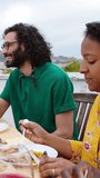Vertical HD video of young group of people enjoying bbq lunch at terrace on summer party. Happy millennial friends gathered on a home rooftop to celebrate. Friendship and celebration concept.