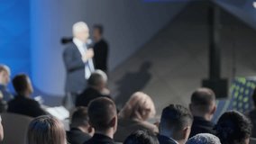 A focused image showing a senior businessman addressing an audience at a corporate event. The foreground is blurred with clear view of the speaker. - Powered by Shutterstock - Get 15% off with code: PIKWIZARD15