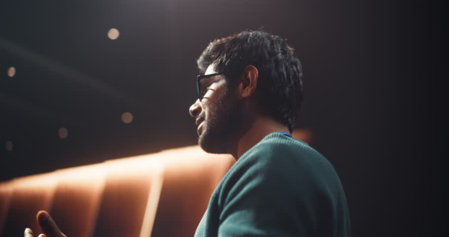 Portrait of a Young Speaker Standing on a Conference Stage. Technology Startup Founder Using a Laptop Computer, Speaking About Software Integration at a Business Meeting with Professional Audience