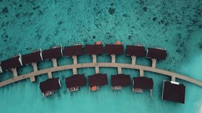 Drone top down rotating video of a tropical resort in the Maldives, blue lagoon reef, sunny weather, turquoise shallow water, water villas, island wooden road, 4K