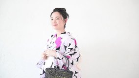 Cute Japanese woman in yukata with gathered hair. Easy-to-use white background (white background) video. She is standing with a smile.