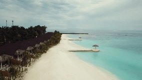 Drone video of a tropical resort in the Maldives, blue lagoon, green palms, turquoise shallow water, island 4K