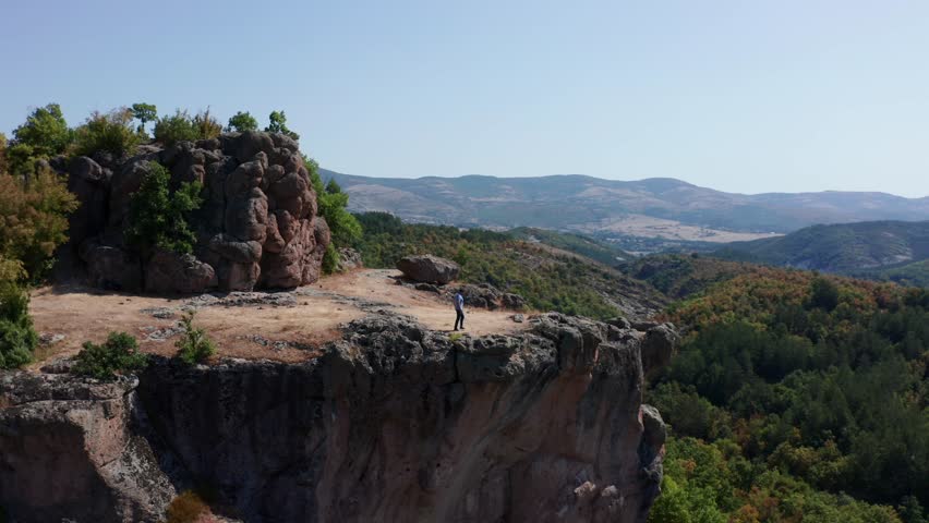Hiker Over Steep Rocky Plateau At Harman Kaya Thracian Sanctuary In Bulgaria. Aerial Drone Shot