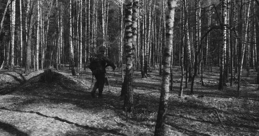 Reenactor Dressed As German Infantry Soldier Going By Forest. Soldier With Carabines Mauser 98k Combing Forest Autumn Season. Reenactment Tactic Game. Wermacht Military Uniform. Black And White Video.