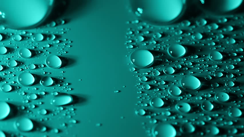 Many small water droplets on the turquoise surface. Large drops absorbing small