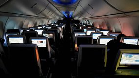 Inside View of an Airplane Cabin at Night, Nighttime inside view of an airplane cabin, showcasing rows of seat-back entertainment screens illuminated in dim cabin light. - Powered by Shutterstock - Get 15% off with code: PIKWIZARD15