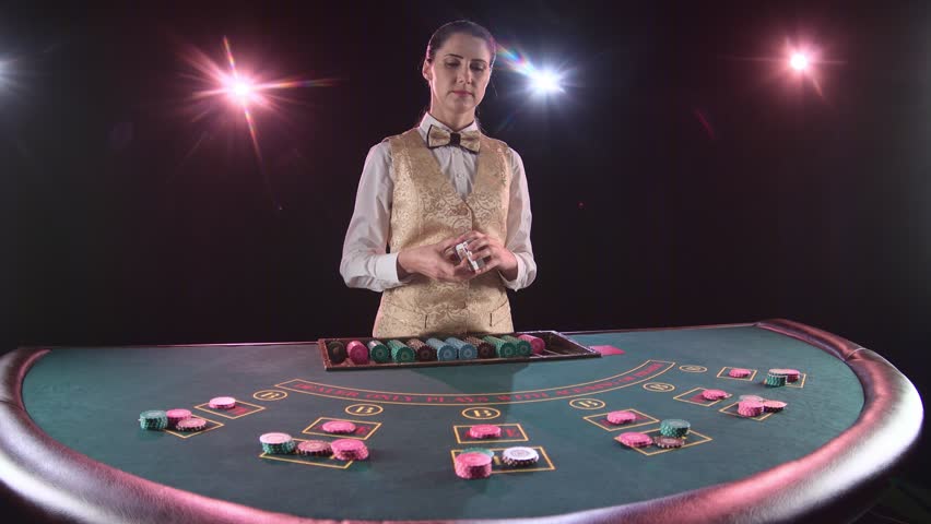 Casino dealer woman shuffles the poker cards and performing trick with cards. Black background. Slow motion