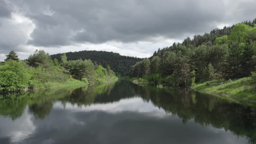 Overcast Weather Reflection On Black River Water Among Dark Green Forest - Aerial Drone Shot