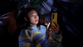 Earnest Asian girl lying on sofa at home using cell phone. Serious discouraged young Chinese woman watching social media app bored on mobile at night. Leisure and online technology in z generation.  - Powered by Shutterstock - Get 15% off with code: PIKWIZARD15