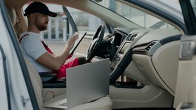 Seated inside car laptop automotive technician conducts diagnostic tests vehicle's malfunction auto service. Inside vehicle master mechanic utilizes laptop diagnose car's problem auto service center. - Powered by Shutterstock - Get 15% off with code: PIKWIZARD15