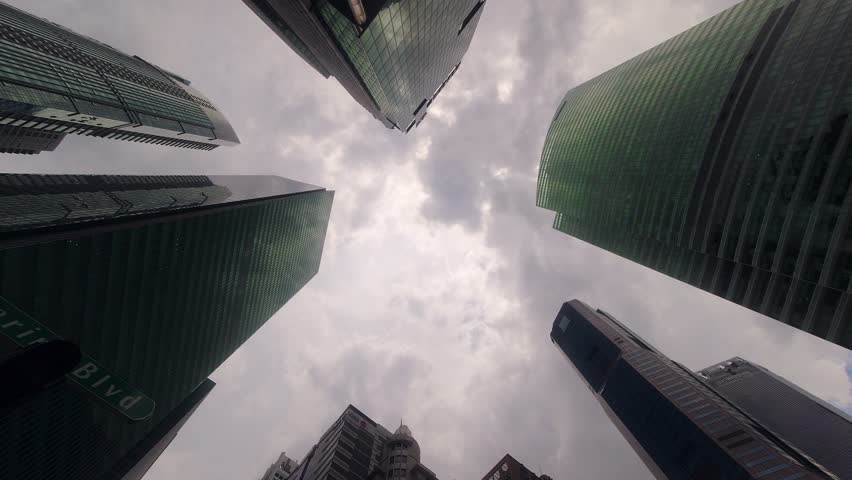 Singapore city- 16th march, 2023:static looking up Singaporean downtown central Business district.Financial skyscraper buildings in Singapore with moving clouds and sun in the sky