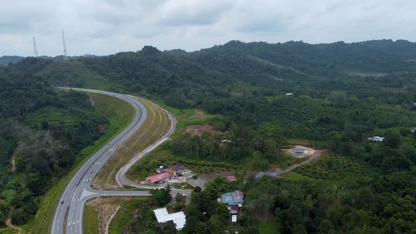 Aerial View of Pan Borneo Highway next to houses and orchards at Bukit Sebangkoi, Sarawak. Royalty-Free Stock Footage #3502099987