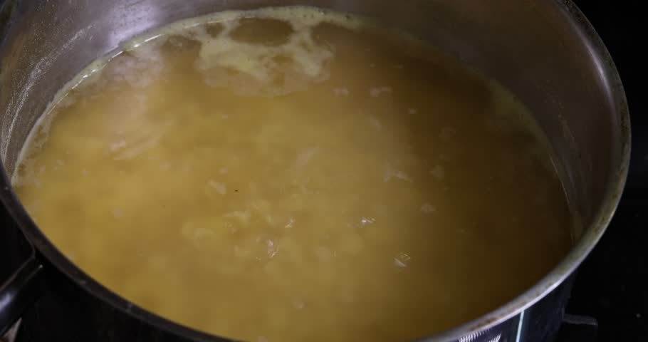 Boling cooking red lentil dal in pot of water bubbling moving 