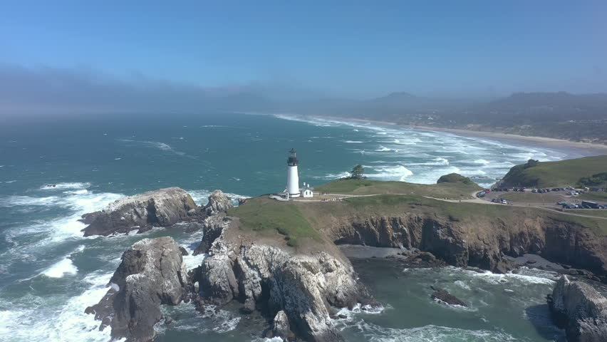 Yaquina Head Lighthouse Newport Oregon Coast. Slow drone orbit around rocks and cliffs.
