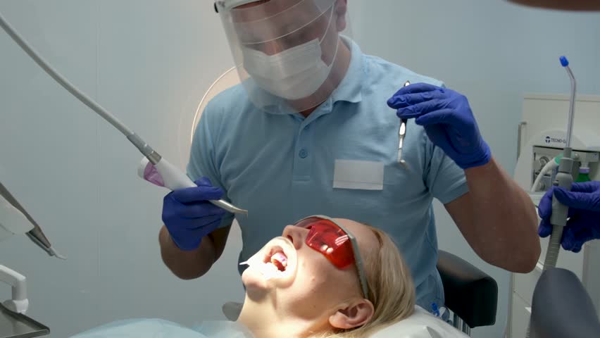 professional teeth cleaning in a dental clinic, removing stones and plaque, young specialists working with a woman, cleaning a saliva ejector, sucking out saliva, applying paint to the teeth Royalty-Free Stock Footage #3502194959