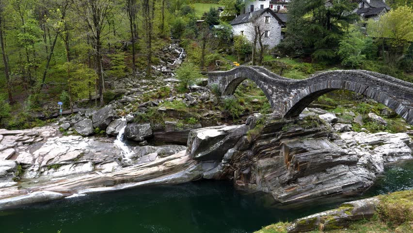 Famous bridge in between forest verzasca, lavertezzo. bridge calls ponte dei salti. You see the beautiful clear green water with a little waterfall. the stones and rocks are unique.