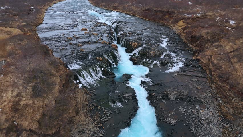 Icy Bruarfoss Waterfall cutting through brown Icelandic terrain, aerial view Royalty-Free Stock Footage #3502316979