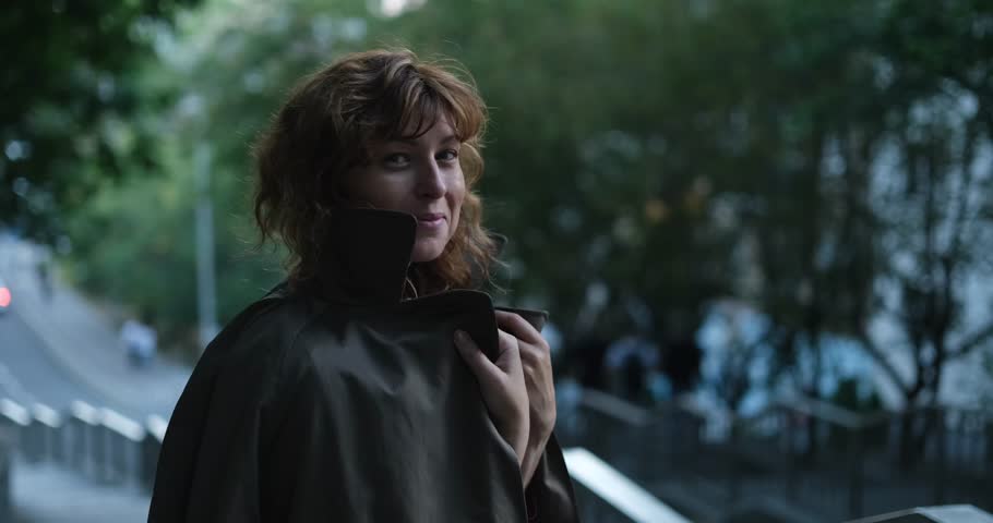Female redhead caucasian girl modelling outdoor with freedom and positive minded wearing trendy trench. Portrait of a happy smiling woman at the stairs with urban background